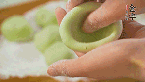 將均分的艾草面團搓成圓，挖一個窩，放入餡心，再搓成圓。