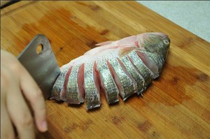 將鱸魚清洗干凈，從脊椎處切斷至腹部，腹部保留1cm左右不要切斷。