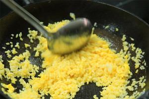 大火加熱炒鍋，再入油，燒到四至五成熱時倒入雞蛋液，在未凝結之前，加米飯煸炒，不停翻炒并用鍋鏟將成塊的米飯碾開、撥散。