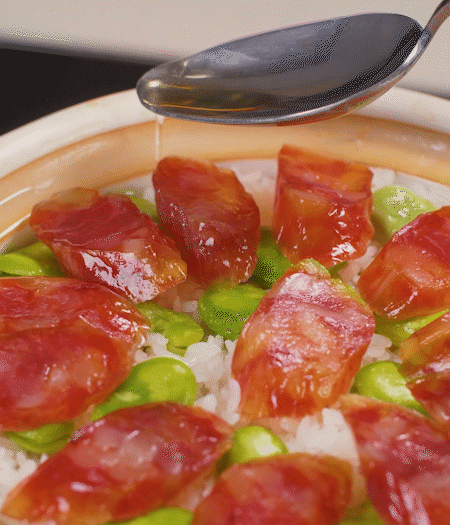 大米出現(xiàn)小孔時開蓋放香腸，往鍋邊淋入少許油，再燜煮8~10分鐘左右。