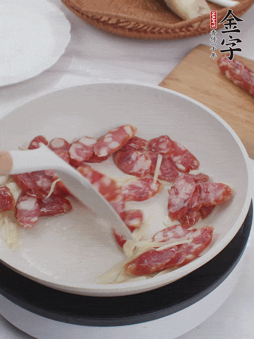 油溫3成熱時(shí)，下姜絲、蒜片、香腸炒出油脂。