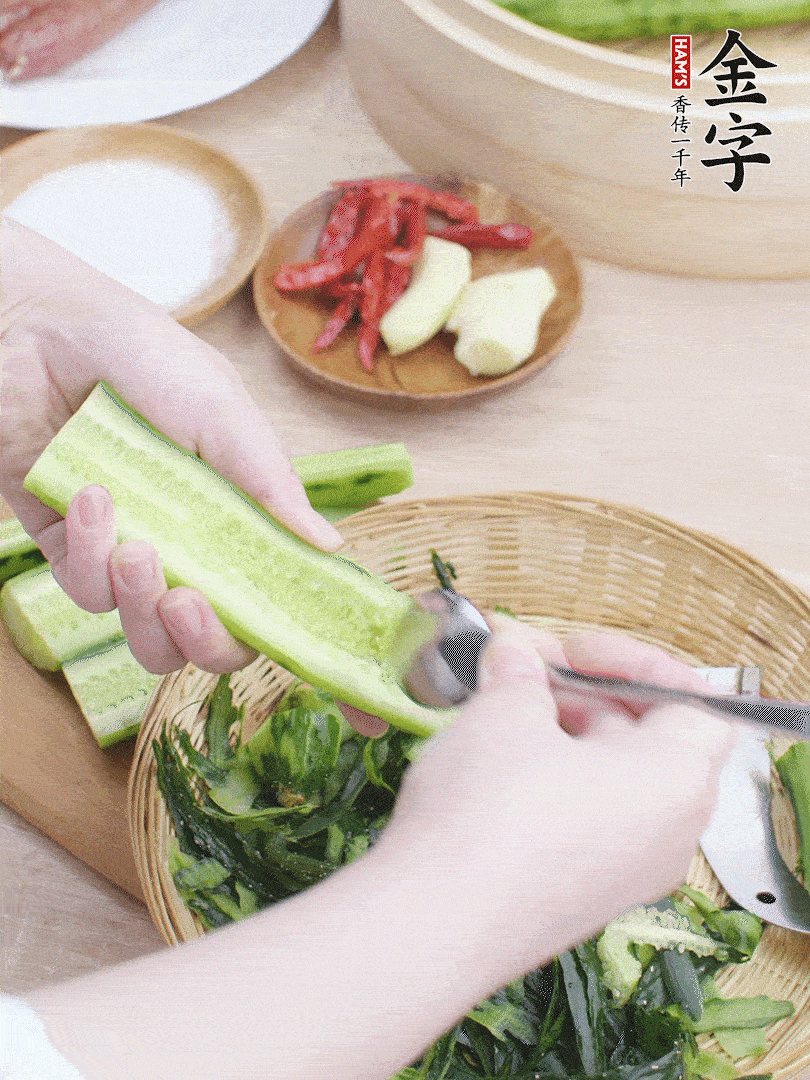 黃瓜削皮，對半切開，勺子挖去內(nèi)瓤，斜刀切片。青蒜斜刀切段。